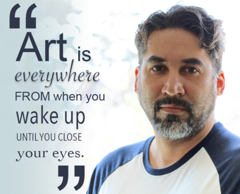 Artist Alejandro with salt and pepper beard close cropped hair and a blue and white baseball shirt. His quote reads "Art is everywhere from when you wake up until you close your eyes."