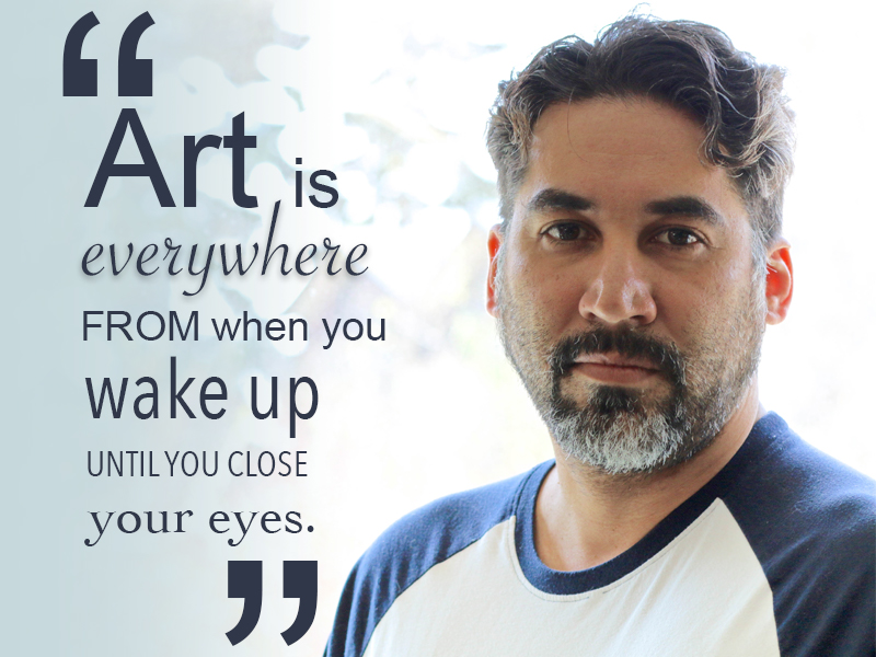 Artist Alejandro with salt and pepper beard close cropped hair and a blue and white baseball shirt. His quote reads "Art is everywhere from when you wake up until you close your eyes."