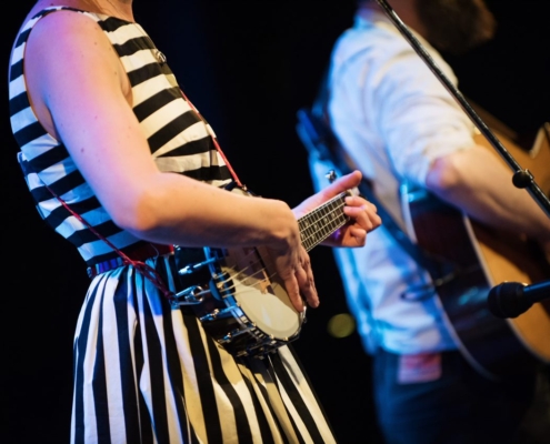 A woman playing a banjo and a man a guitar