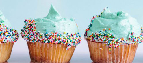 Four frosted cupcakes with green icings and sprinkles