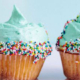 Four frosted cupcakes with green icings and sprinkles