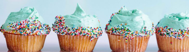 Four frosted cupcakes with green icings and sprinkles