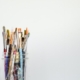 pencil crayons and paint brushes in a clear glass