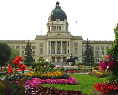 SK Legislative building behind a yard of flowerbeds and a grass walkway