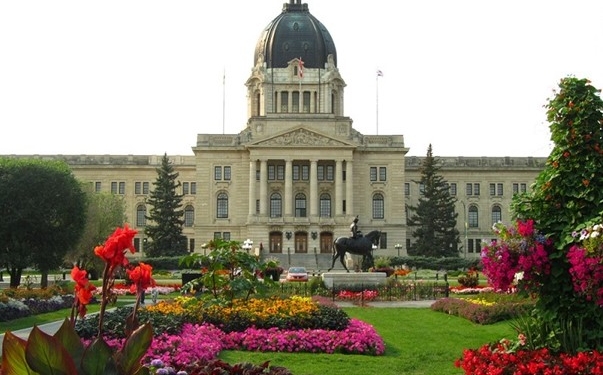 SK Legislative building behind a yard of flowerbeds and a grass walkway