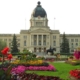 SK Legislative building behind a yard of flowerbeds and a grass walkway