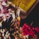 paint brushes in a cup beside a vase of flowers