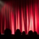 Red Theatre curtains closed in front of a darkened theatre