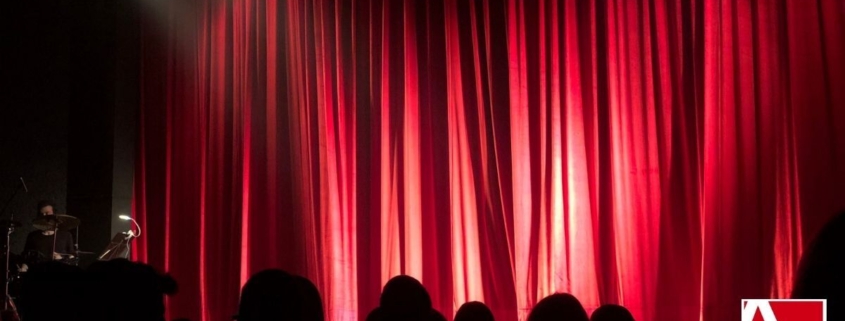 Red Theatre curtains closed in front of a darkened theatre