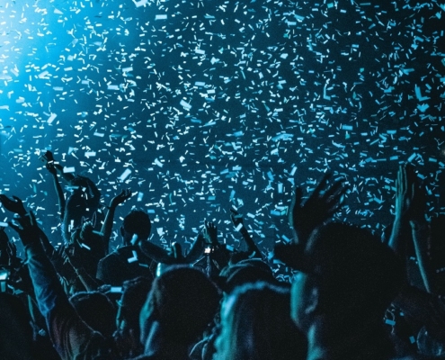 A crowd in blue lighting with confetti raining down on them