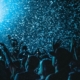 A crowd in blue lighting with confetti raining down on them