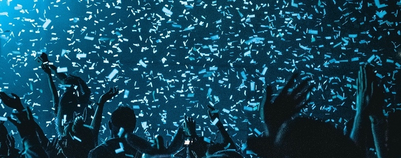 A crowd in blue lighting with confetti raining down on them