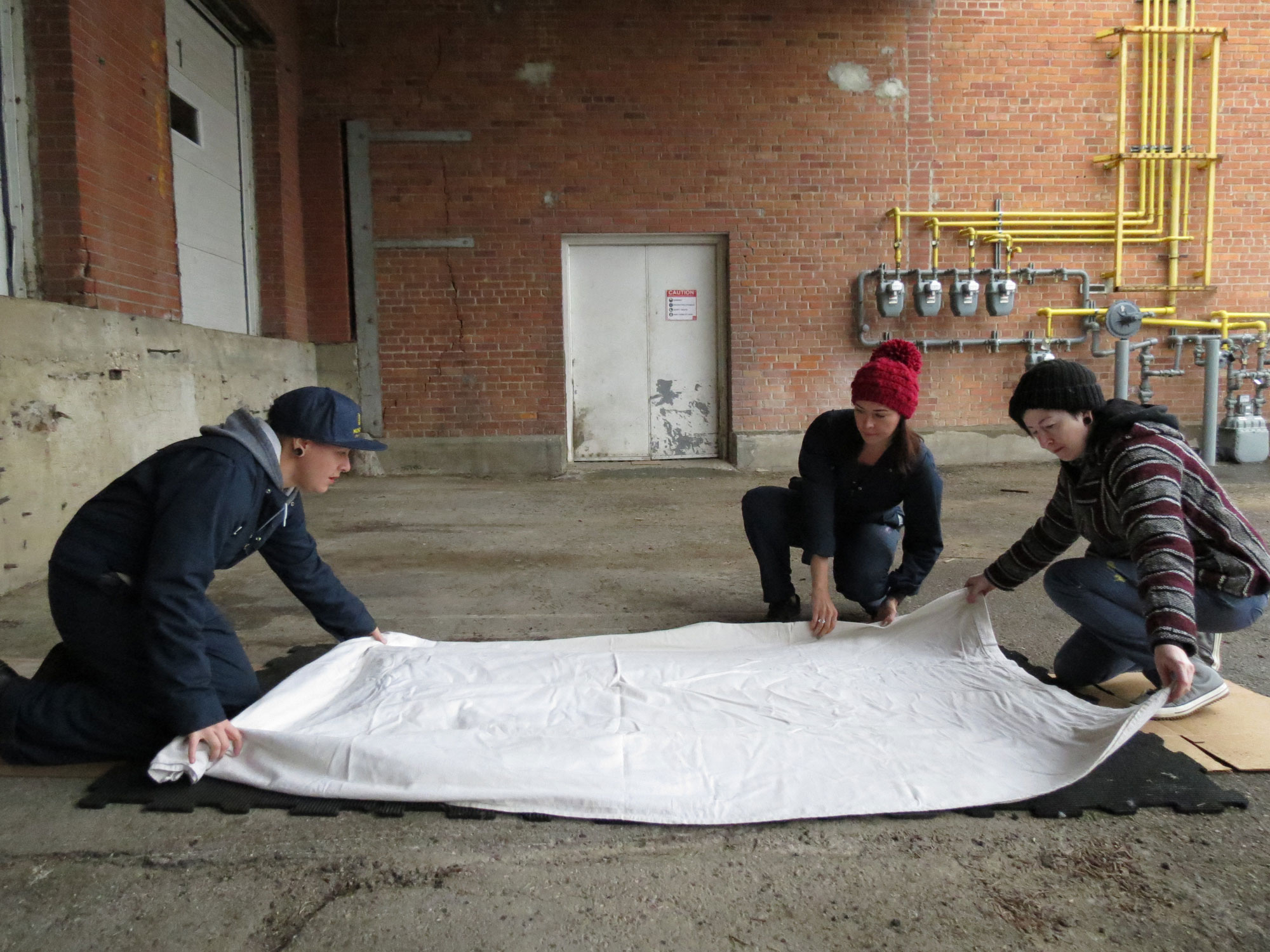Em Ironstar, Caitlin Mullan & Karli Jessup prepare a large-format wood block to be printed with a steamroller.