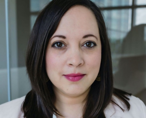 Headshot of Tara with dark shoulder length hair and white top