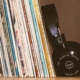 Spines of vinyl records in cardboard cases leaning to the left with black headphones against the records