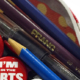 A red pencil case with zipper open and pencil crayons and SAA buttons spilling out
