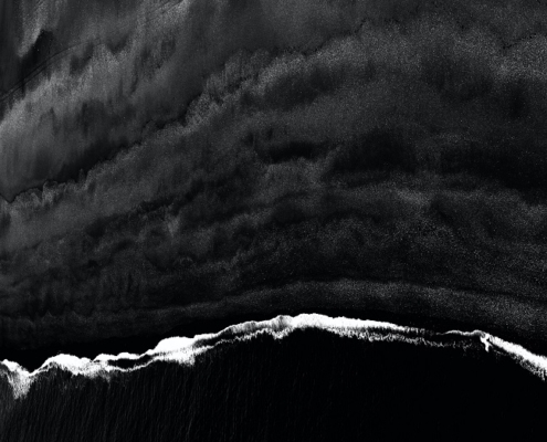 Black and white image of waves hitting the shores - viewpoint from the top.