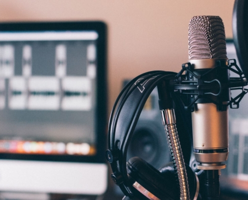 recording equipment including headphones hanging on a microphone - a laptop in the background