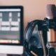 recording equipment including headphones hanging on a microphone - a laptop in the background