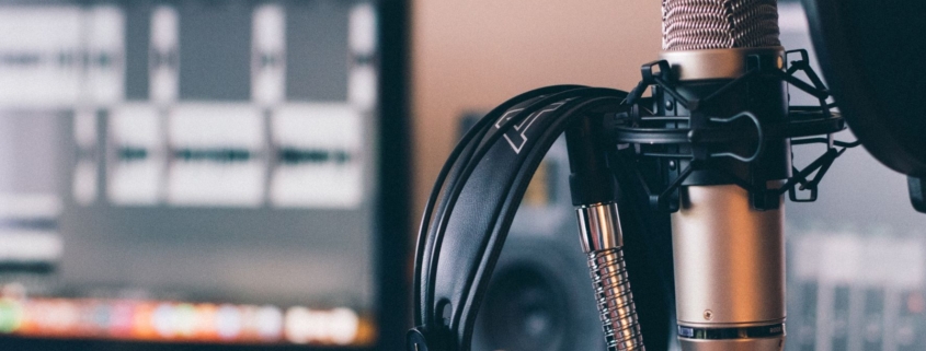 recording equipment including headphones hanging on a microphone - a laptop in the background