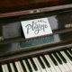 piano with an open keyboard. Above the centre of the piano - above the keys is a hand written note that reads "go ahead, play me."