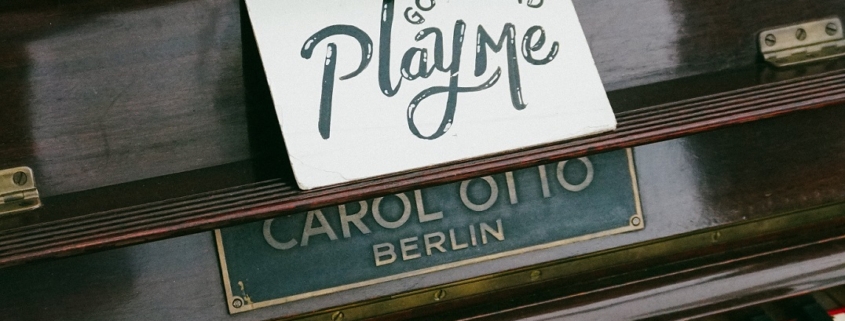 piano with an open keyboard. Above the centre of the piano - above the keys is a hand written note that reads "go ahead, play me."