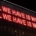 Red lighting against a black background reading "All we have is words. All we have is worlds"