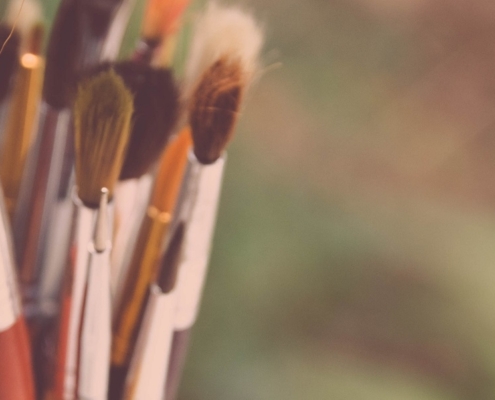 A cup filled with dry paint brushes