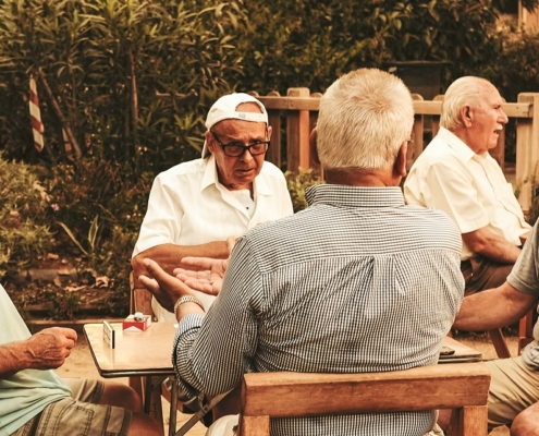 Senior men sitting around an outdoor table in a collective activity.