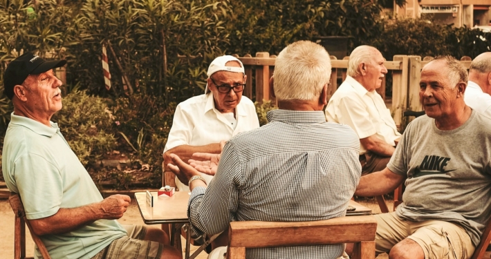 Senior men sitting around an outdoor table in a collective activity.