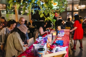 Group of people surrounding a table with arts supplies ready to be used.