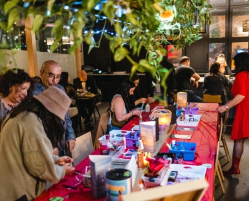 Group of people surrounding a table with arts supplies ready to be used.