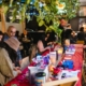 Group of people surrounding a table with arts supplies ready to be used.