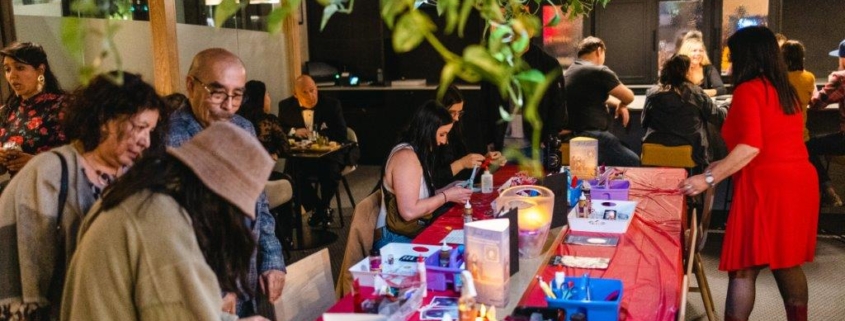 Group of people surrounding a table with arts supplies ready to be used.