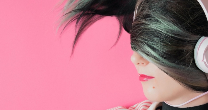 a woman with her hair draped over the top half of her face is earing pig headphones on a pink background