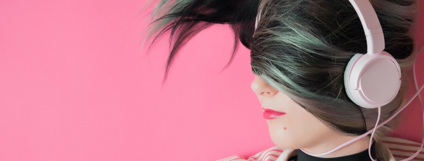 a woman with her hair draped over the top half of her face is earing pig headphones on a pink background