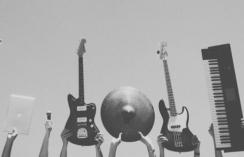 grey image of multiple instrument being held up into the frame by multiple people