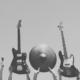 grey image of multiple instrument being held up into the frame by multiple people