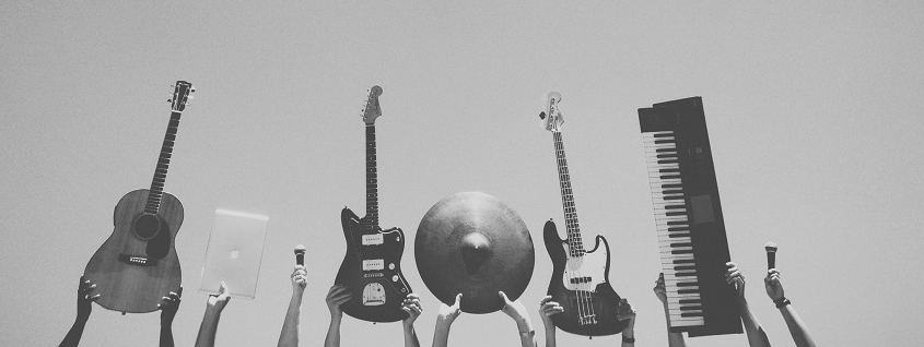 grey image of multiple instrument being held up into the frame by multiple people