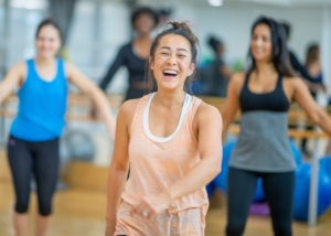 Woman in forefront of a dance class. Laughing.