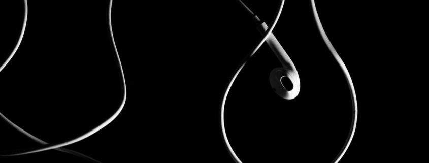 black and white photo of white wired earbuds