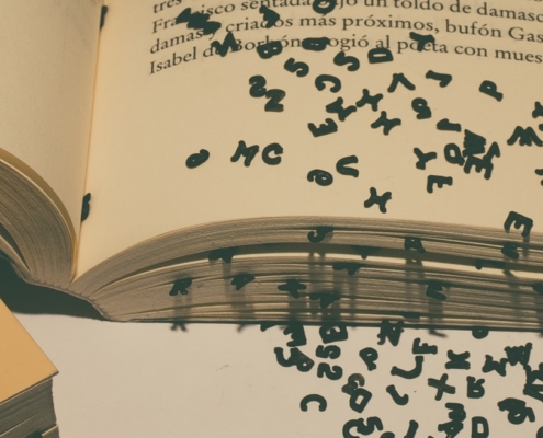 On open book with black text letters falling out of the pages.