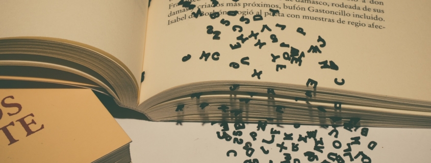 On open book with black text letters falling out of the pages.
