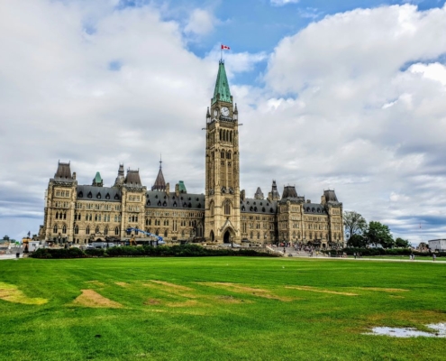Canadian Parliament against a cloudy blue sky.