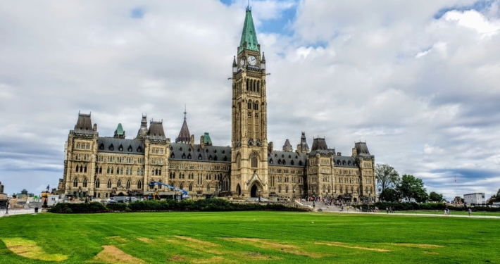 Canadian Parliament against a cloudy blue sky.