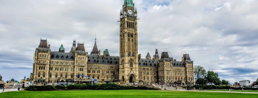 Canadian Parliament against a cloudy blue sky.