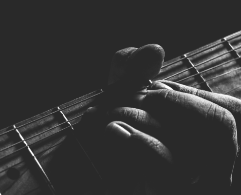 black and white image of a guitar with a hand holding it.