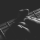 black and white image of a guitar with a hand holding it.