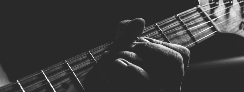 black and white image of a guitar with a hand holding it.