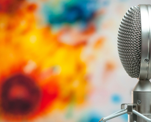 Metal double sided microphone in the foreground with a blurred painting in the background